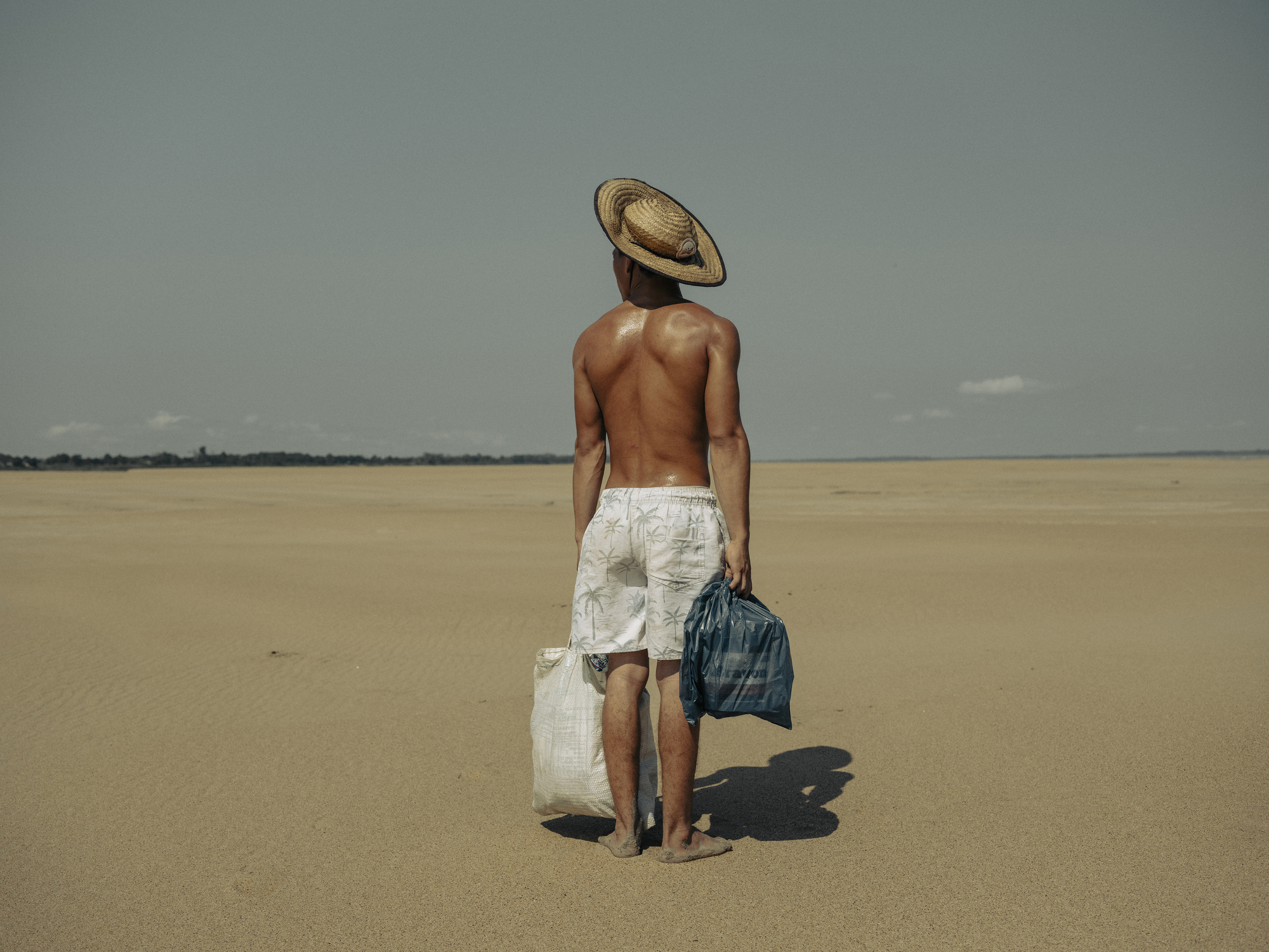 2024年10月5日，巴西亞馬遜州（Amazonas），一名年輕男子步行超過2公里的乾涸河床，前往馬納卡普魯（Manacapuru）村落探望母親。該村過去可經水路抵達，但因旱災已無法通行。（攝影／Musuk Nolte／Panos Pictures／Bertha Foundation）